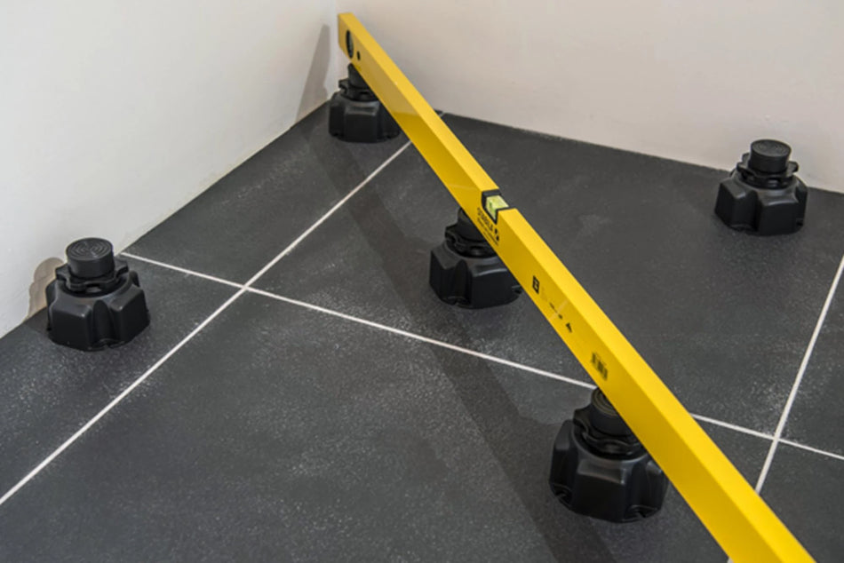 Multiple black adjustable riser feet under rectangular shower tray